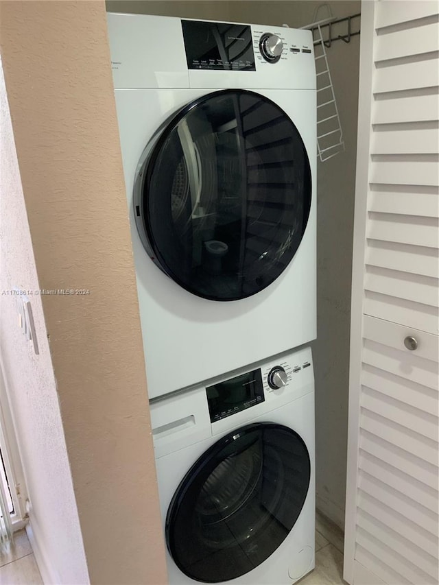 laundry area with light tile patterned flooring and stacked washer and dryer