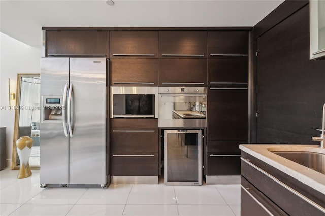 kitchen with dark brown cabinets, beverage cooler, stainless steel appliances, and light tile patterned floors