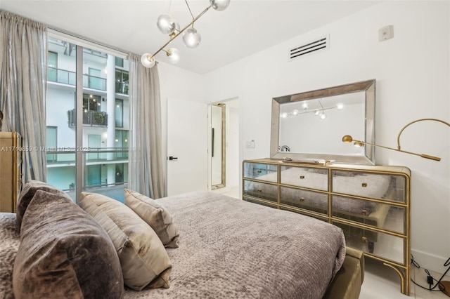 bedroom with a wall of windows and a chandelier