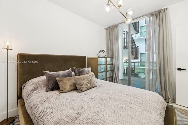 bedroom with access to outside and a chandelier