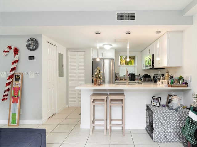 kitchen featuring white cabinetry, stainless steel appliances, kitchen peninsula, pendant lighting, and a breakfast bar area