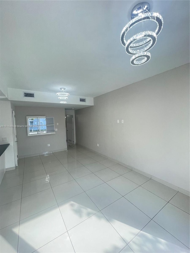 tiled empty room with a chandelier