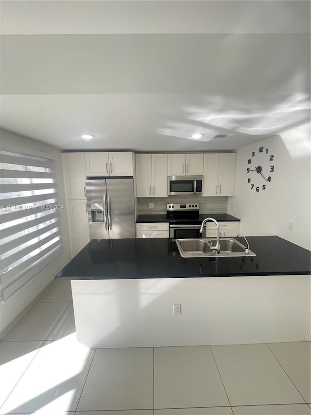 kitchen featuring sink, light tile patterned floors, backsplash, white cabinets, and appliances with stainless steel finishes