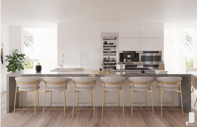 kitchen featuring a breakfast bar, light hardwood / wood-style floors, white cabinetry, and sink