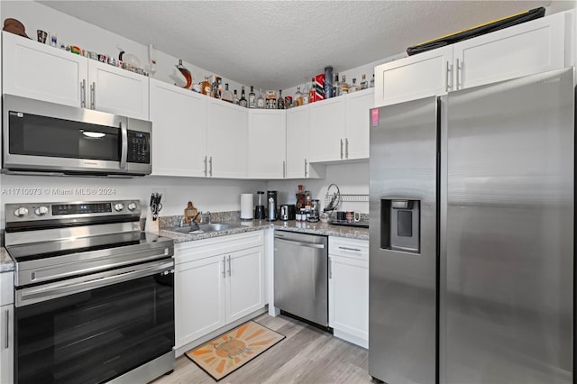 kitchen with light stone countertops, white cabinetry, and stainless steel appliances