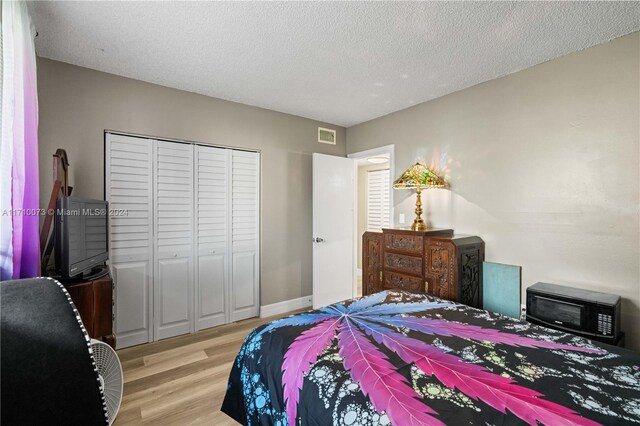 bedroom featuring a closet, a textured ceiling, and light wood-type flooring