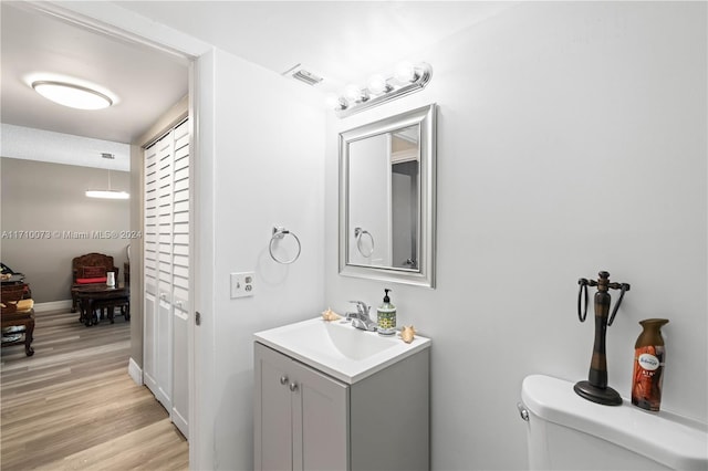 bathroom with hardwood / wood-style floors, vanity, and toilet