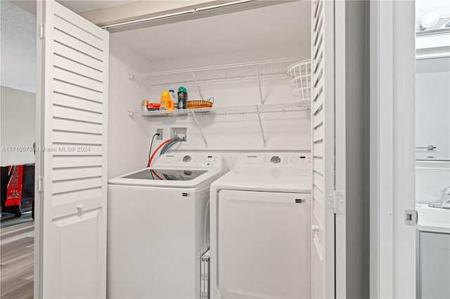 clothes washing area with washing machine and dryer, hardwood / wood-style flooring, and sink