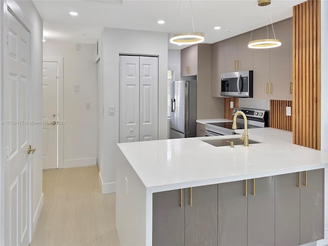 kitchen with gray cabinetry, sink, hanging light fixtures, stainless steel appliances, and light hardwood / wood-style floors