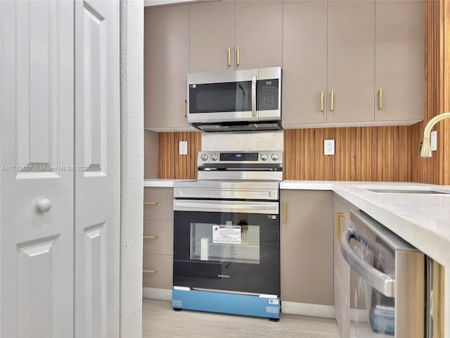 kitchen featuring gray cabinets, light hardwood / wood-style flooring, stainless steel appliances, and sink