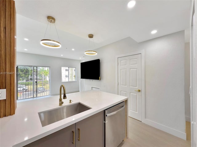 kitchen featuring stainless steel dishwasher, decorative light fixtures, light wood-type flooring, and sink