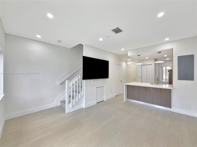 unfurnished living room with electric panel, light hardwood / wood-style flooring, and sink