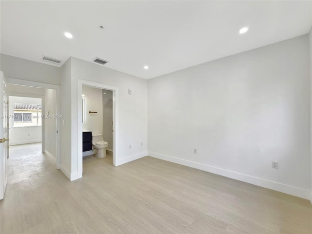 unfurnished bedroom featuring light wood-type flooring and connected bathroom