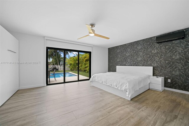 bedroom featuring ceiling fan, access to exterior, a wall mounted AC, and light hardwood / wood-style flooring