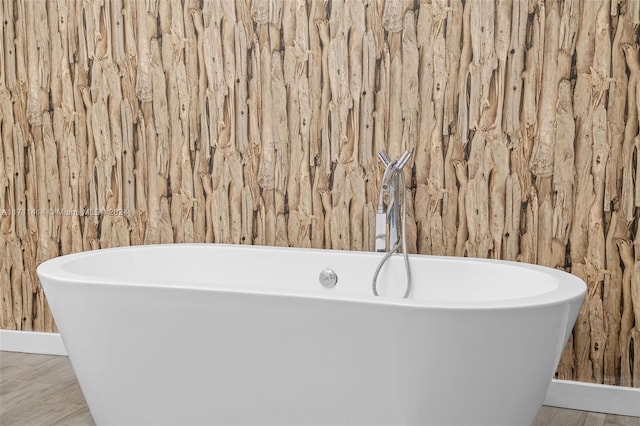 bathroom featuring a bath and wood walls