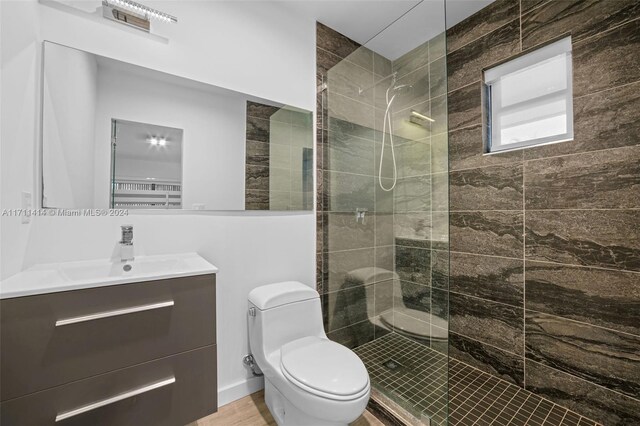 bathroom with vanity, tiled shower, and toilet