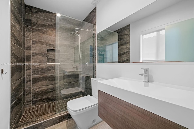 bathroom featuring tiled shower, vanity, and toilet