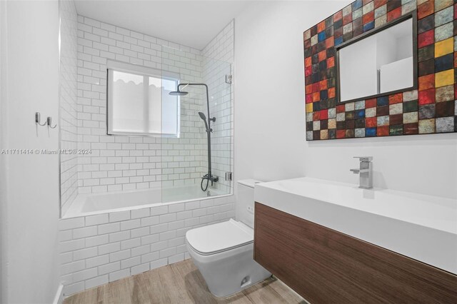 full bathroom with wood-type flooring, toilet, tiled shower / bath combo, and vanity