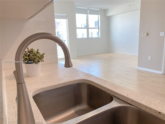 room details with light stone countertops, sink, and light hardwood / wood-style floors