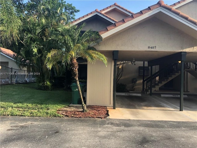 view of exterior entry with a lawn and a carport