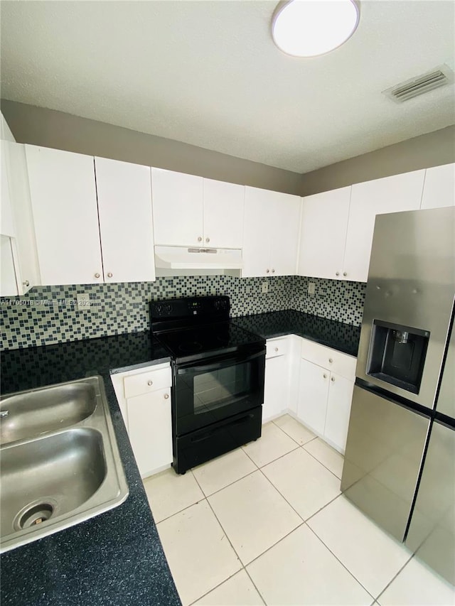 kitchen with sink, black / electric stove, stainless steel fridge, white cabinets, and backsplash