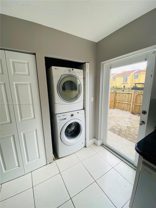 laundry room featuring light tile patterned floors, a textured ceiling, and stacked washing maching and dryer