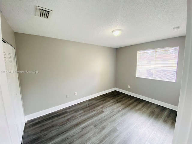 unfurnished room with a textured ceiling and dark hardwood / wood-style flooring