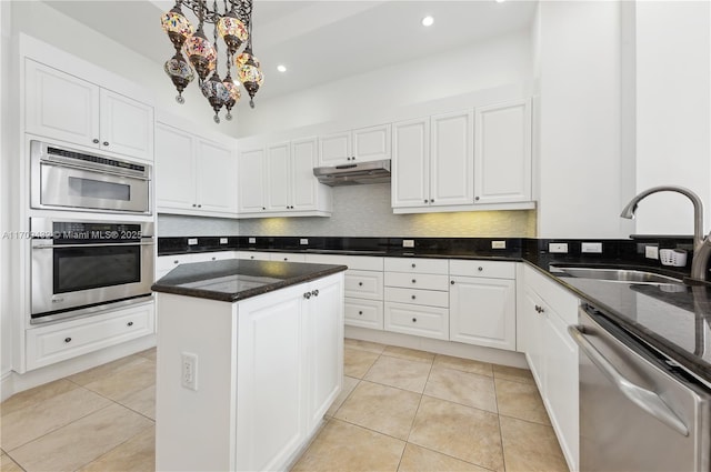 kitchen with sink, a center island, stainless steel appliances, light tile patterned floors, and white cabinets