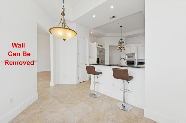 kitchen with a kitchen bar, kitchen peninsula, white cabinetry, and pendant lighting