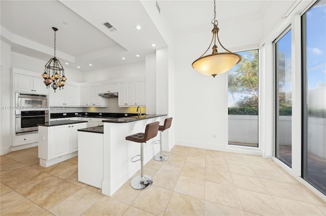 kitchen featuring pendant lighting, a kitchen bar, white cabinetry, and kitchen peninsula