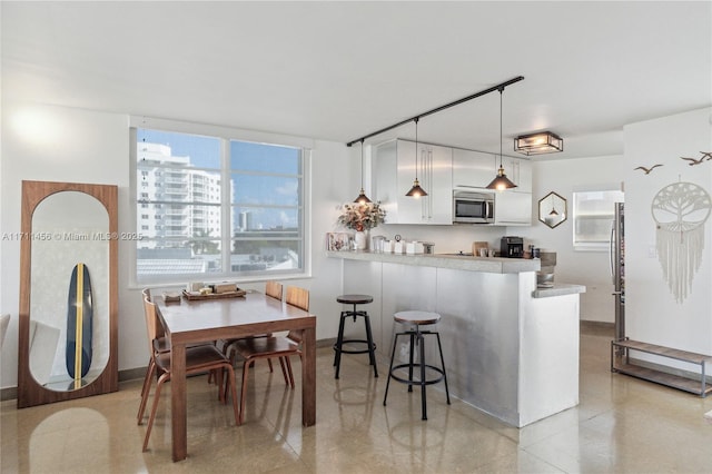 kitchen featuring a peninsula, white cabinetry, light countertops, appliances with stainless steel finishes, and pendant lighting