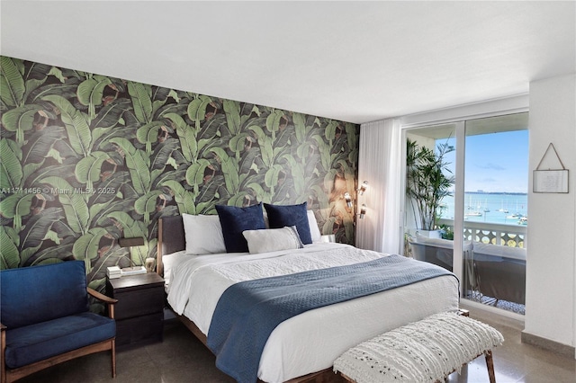 bedroom featuring wallpapered walls, baseboards, an accent wall, a water view, and access to exterior