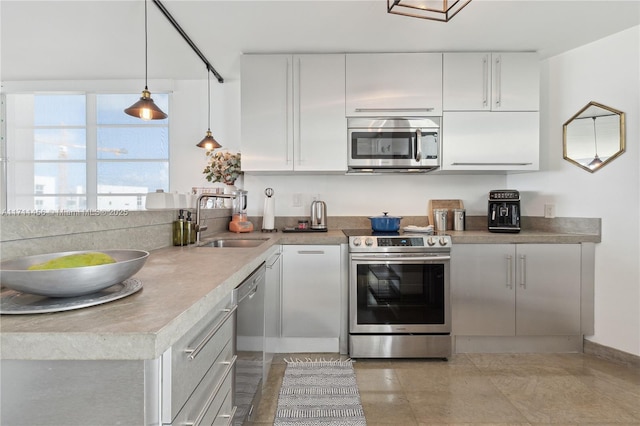 kitchen featuring pendant lighting, light countertops, appliances with stainless steel finishes, white cabinets, and a sink