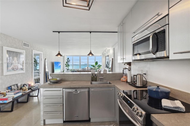 kitchen with visible vents, appliances with stainless steel finishes, a peninsula, pendant lighting, and a sink