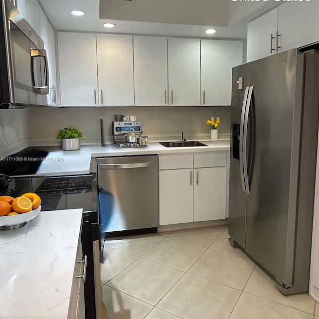 kitchen featuring stainless steel appliances, white cabinetry, sink, and light tile patterned flooring