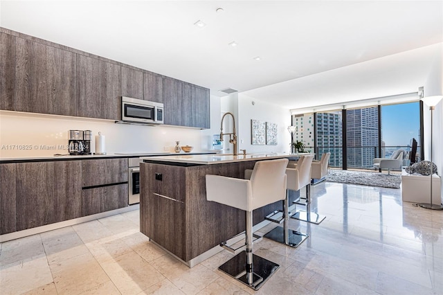 kitchen with sink, an island with sink, a breakfast bar area, and stainless steel appliances