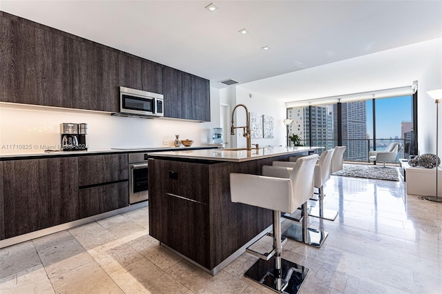 kitchen featuring a kitchen breakfast bar, sink, an island with sink, and appliances with stainless steel finishes