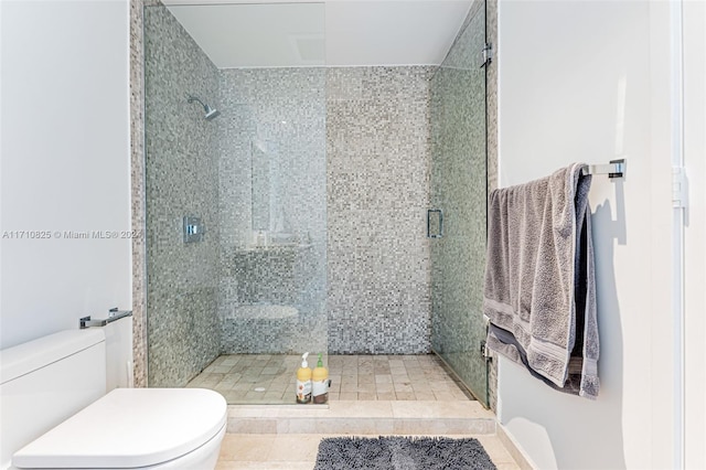 bathroom with tile patterned flooring, toilet, and a shower with shower door