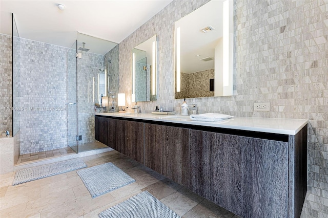 bathroom with a tile shower, vanity, and tile walls