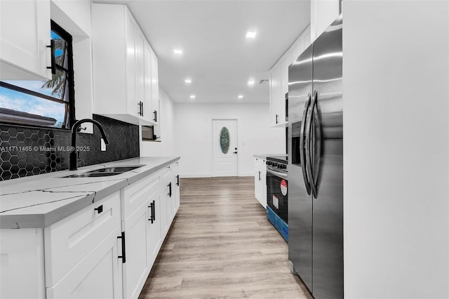 kitchen with white cabinets, sink, light stone countertops, and stainless steel appliances