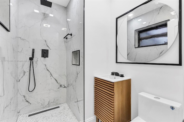 bathroom with toilet, vanity, and tiled shower