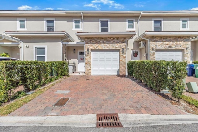 townhome / multi-family property with a wall mounted AC and a garage