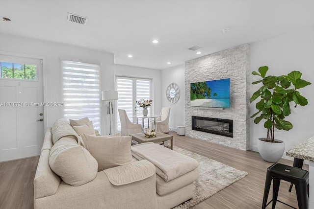 living room with light hardwood / wood-style flooring and a stone fireplace