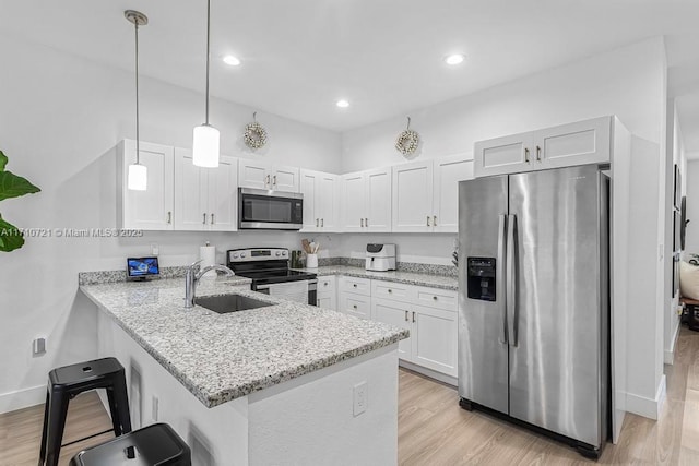 kitchen featuring decorative light fixtures, appliances with stainless steel finishes, white cabinetry, and kitchen peninsula