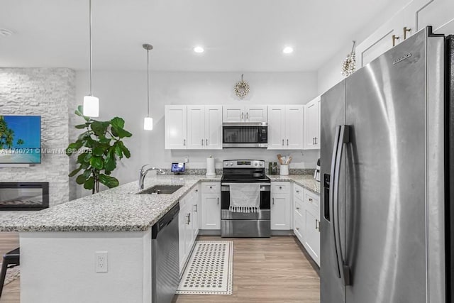 kitchen with white cabinetry, pendant lighting, stainless steel appliances, and sink