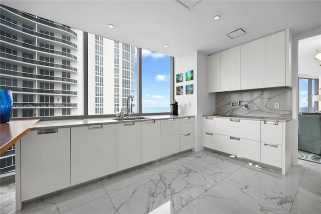 kitchen featuring white cabinets, backsplash, sink, and a wealth of natural light