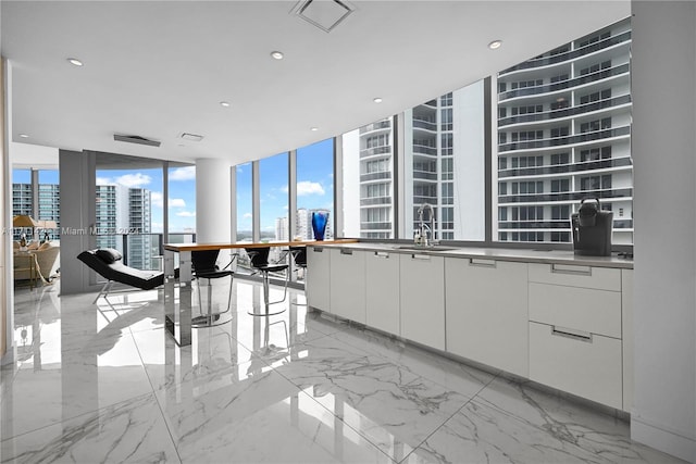 kitchen with a wall of windows, white cabinetry, and sink