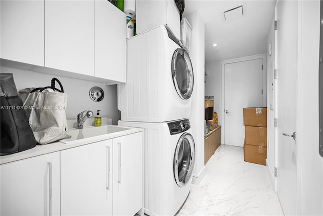 laundry room with cabinets, stacked washing maching and dryer, and sink