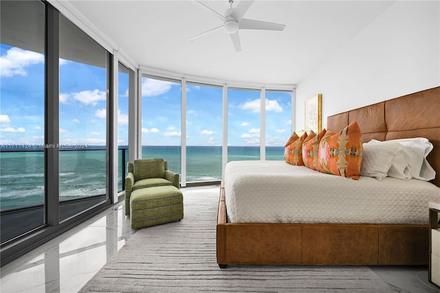 bedroom with multiple windows, a water view, and a wall of windows