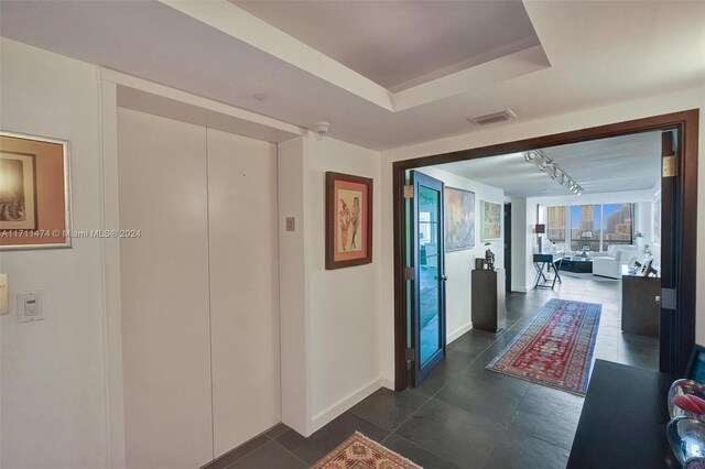 hallway with a raised ceiling and rail lighting